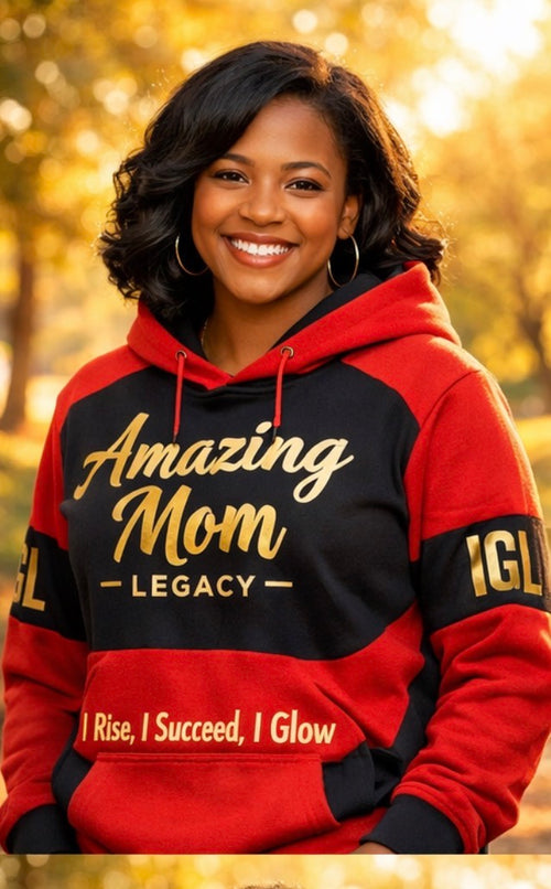 Woman wearing a red and black hoodie with 'Amazing Mom Legacy' text, standing outdoors with blurred foliage in the background.