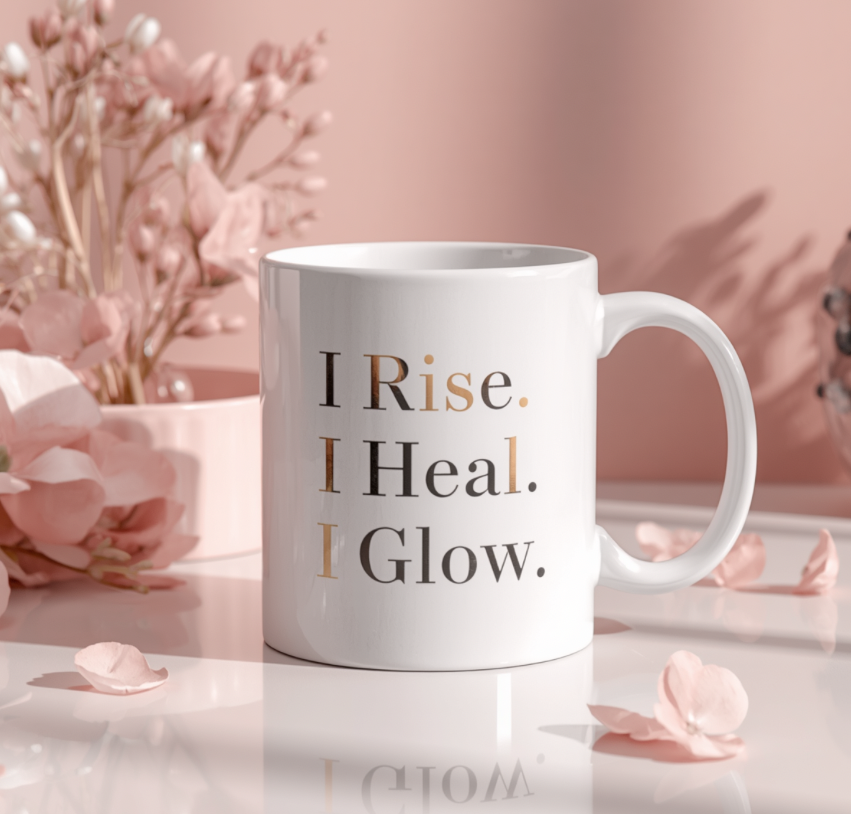 White mug with 'I Rise. I Heal. I Glow.' text on a pink floral background