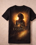 Black t-shirt with a graphic of a woman and text 'I Rise, I Heal, I Glow' on a beige background